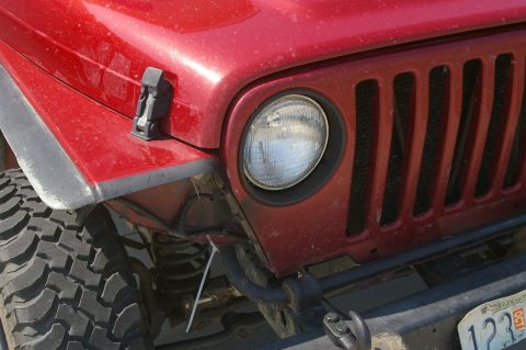 1998 Jeep TJ - Close-up of a red Jeep TJ's front end, showing the grille and headlight assembly.