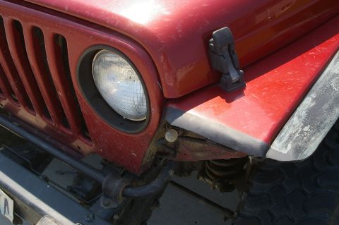1998 Jeep TJ - Front view of a red Jeep TJ, showing the grille and fender detail.