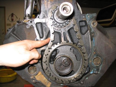 1979 Ford F-150 - A hand points to the timing chain and gears on an engine block.