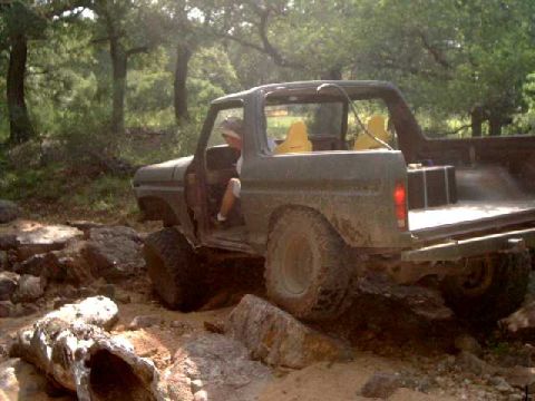 1979 Ford Bronco - This 1979 Ford Bronco navigates a challenging off-road course with large rocks and trees in the background.