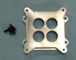 1979 Ford Bronco - A metal carburetor spacer and screws are displayed on a light blue surface.
