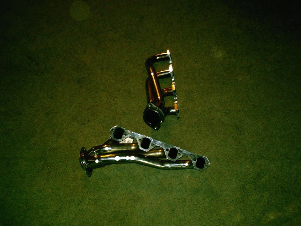 two exhaust manifolds on a green carpet