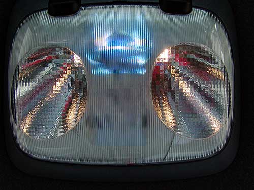 Interior overhead dome light with two lit map lamps behind a ribbed clear lens