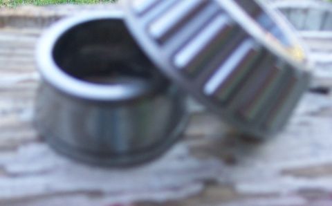 1978 Ford Bronco - Close-up view of two metal bearings, one showing its internal roller cage, on a textured surface.