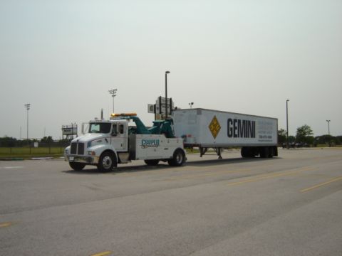1992 Ford Bronco - A white tow truck is seen from the side, towing a white trailer with the 'GEMINI' logo.