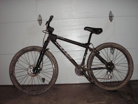 1997 Ford Probe - A black mountain bike is shown in a side profile against a garage door.