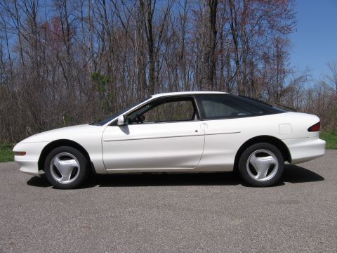 1997 Ford Probe - This 1997 Ford Probe is captured in a side profile, its coupe body style against a backdrop of trees.