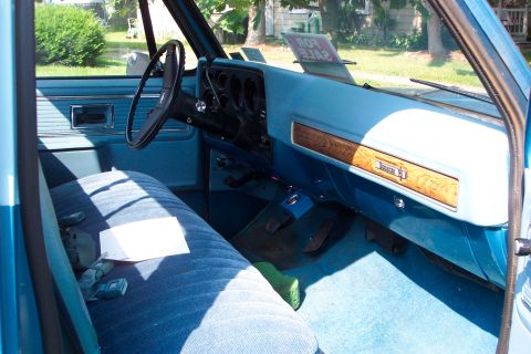 1979 Ford F-150 - Interior view of a 1979 Chevrolet pickup truck, a blue bench seat and dashboard with wood grain accents.