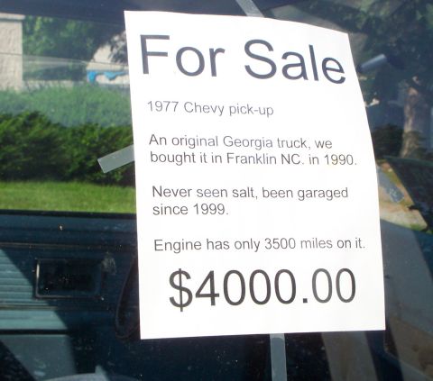 1979 Ford F-150 - A sign on a vehicle's windshield advertises a 1977 Chevy pick-up for sale at $4000.00.