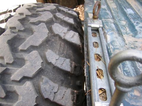 1994 Ford Bronco - Detail of an off-road tire and a tie-down anchor system.