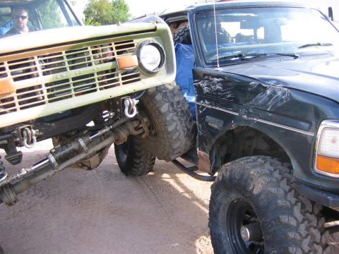 1994 Ford Bronco - Two off-road trucks are shown in a close-up view, one with a damaged fender.