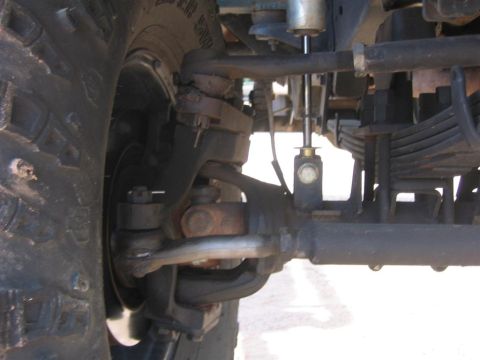 1994 Ford Bronco - Front suspension and tire detail of a 4x4 vehicle, showing steering components and leaf springs.