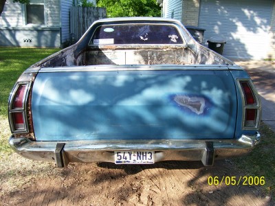 1972 Ford Ranchero - The rear of a blue 1972 Ford Ranchero shows a dented tailgate and a license plate reading 54Y-NH3.