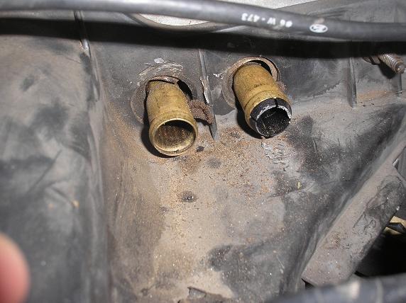 Two brass fittings, one cracked, protrude from a dusty black plastic housing under a cable marked '06 W-473'