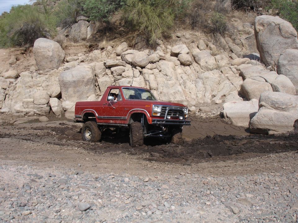 Red 1980s Ford Bronco stuck in mud off-road
