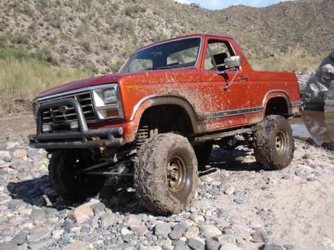 1984 Ford Bronco - Modified Ford Bronco navigating a rocky, off-road environment.
