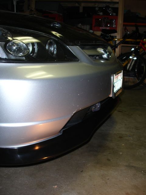 1993 Ford Taurus - Close-up of a car's front end, showing the bumper, headlights, and a black lip spoiler.