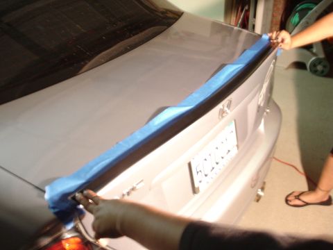1993 Ford Taurus - Someone is preparing the car's trunk lid for a spoiler installation by applying masking tape.
