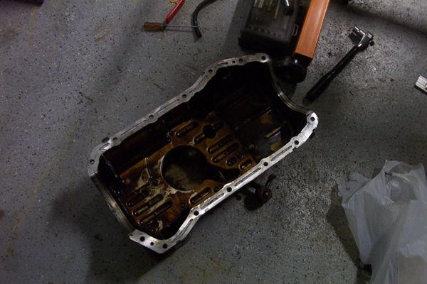 Dirty oil pan on concrete floor with tools
