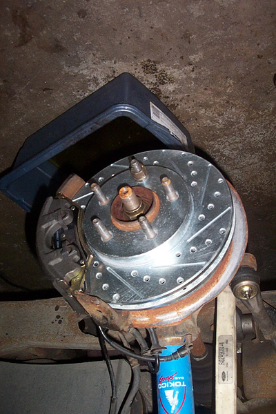 1995 Ford Taurus - A close-up view of a vehicle's brake system, a drilled rotor and caliper.