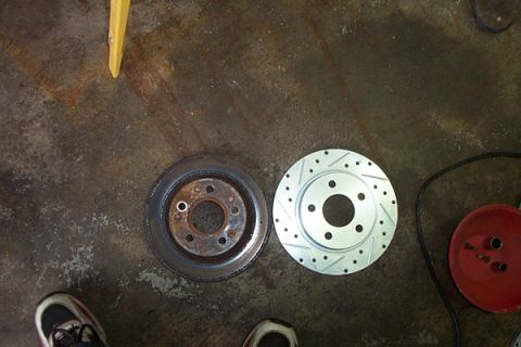 1995 Ford Taurus - Comparison of a worn brake rotor with a new slotted performance rotor, likely for an engine refresh or swap project.