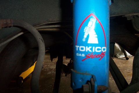 1995 Ford Taurus - Close-up of a blue Tokico gas shock absorber, part of a vehicle's suspension system.