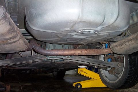 1995 Ford Taurus - The undercarriage of a vehicle is shown, the exhaust pipe, fuel tank, and suspension components.
