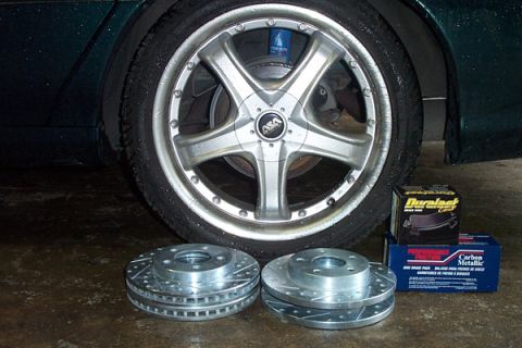 1995 Ford Taurus - New brake rotors and pads are displayed next to a car's wheel, suggesting an upcoming brake system refresh.
