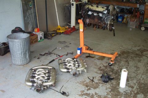 1995 Ford Taurus - Engine components and an engine on a stand are laid out in a garage, suggesting a repair or swap.