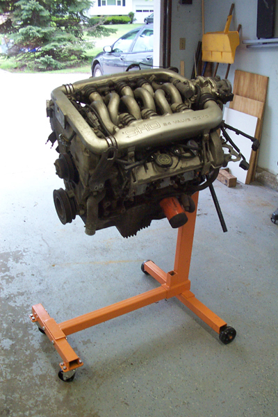 1995 Ford Taurus - Engine on a stand, with a car visible in the background through an open garage door.