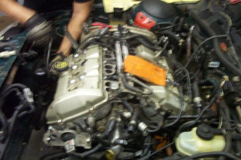 1995 Ford Taurus - Mechanic working on the engine of a vehicle, focusing on the intake manifold and associated components.