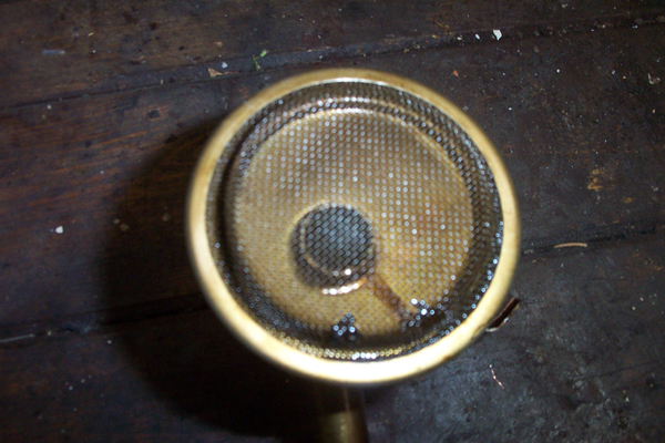 Brass oil pump screen with mesh filter, on a dark wooden surface