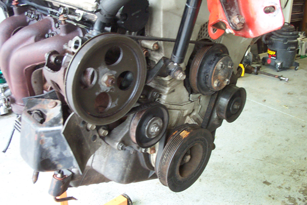 Engine with pulleys and exhaust manifold, mounted on an engine stand