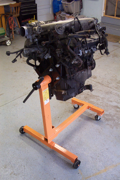 1995 Ford Taurus - An engine is mounted on a portable orange engine stand, ready for work.