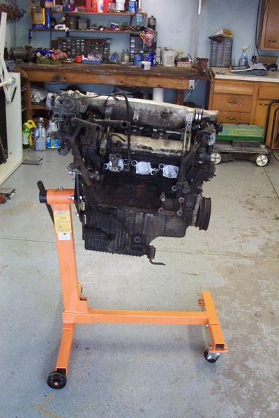 1995 Ford Taurus - Engine on an orange stand in a workshop, showing signs of wear and tear.
