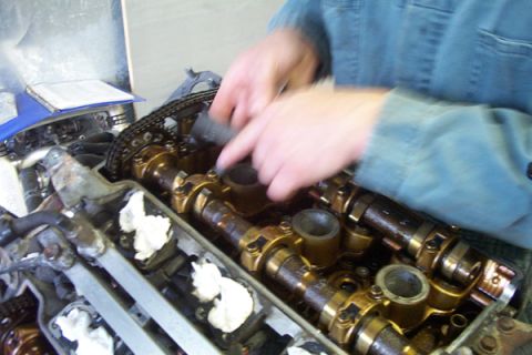 1995 Ford Taurus - Mechanic's hands performing maintenance on an engine's valve train components.