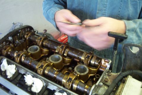 1995 Ford Taurus - Close-up of engine internals with a person performing maintenance on the camshafts.
