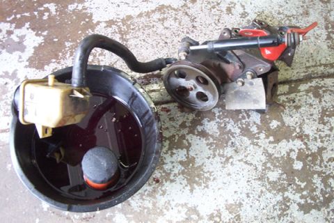 1995 Ford Taurus - A power steering pump and reservoir are shown removed from a vehicle and placed in a drain pan.