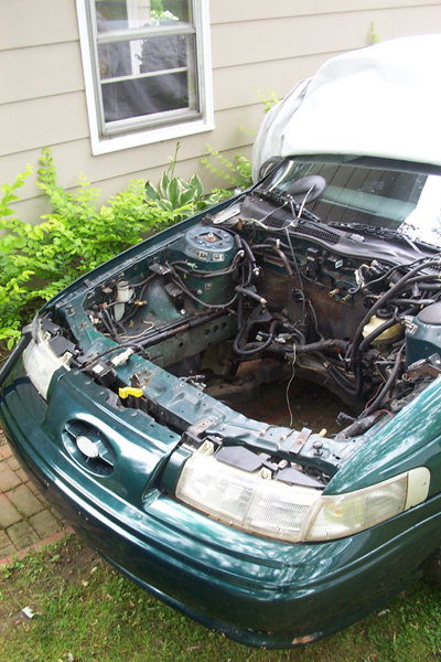 1995 Ford Taurus - The engine bay of a green 1995 Ford Taurus, showing the area where the engine has been removed.