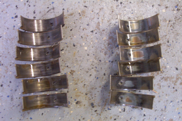 Two stacks of used engine bearing shells on a concrete floor