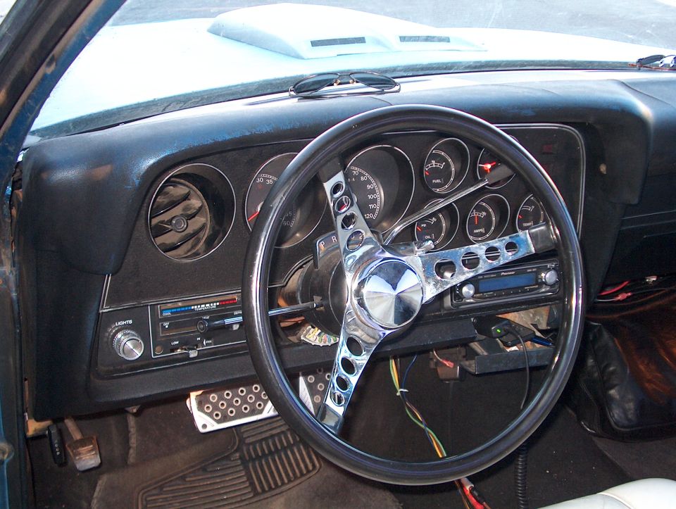 Black dashboard with round gauges, chrome aftermarket steering wheel, and Pioneer stereo in a 1978 Ford Ranchero.