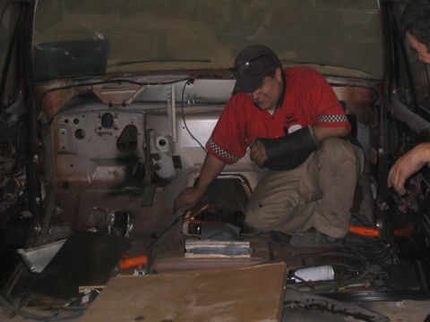 1982 Ford Bronco - Mechanics work on the interior of a vehicle, with exposed dashboard and wiring visible.