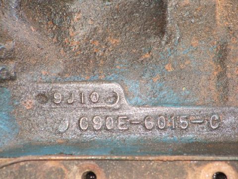 1966 Ford Ranchero - Close-up of a cast-iron engine block casting number reading "C9OE-6015-C" with a date code "9J10" above it, on a surface with faded blue-gr…