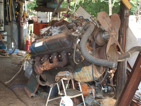 1972 Ford Ranchero - A V8 engine assembly, showing signs of rust and age, is displayed in a cluttered workshop environment.