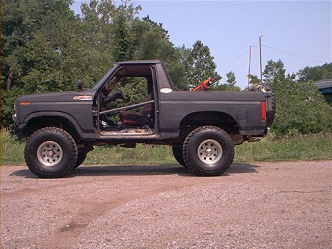 1986 Ford Bronco - Modified 1986 Ford Bronco shown from the side with its doors removed and a roll cage visible inside.