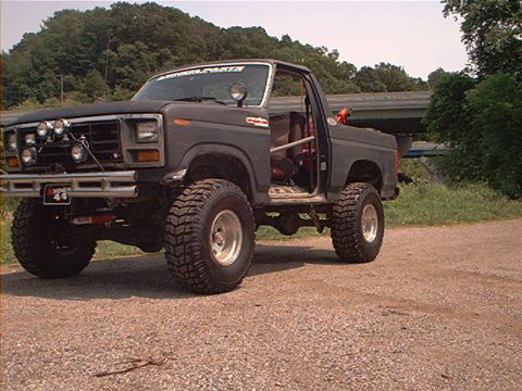 1986 Ford Bronco - This lifted SUV features aggressive off-road tires, a roll cage, and auxiliary lights, suggesting it's built for terrain.