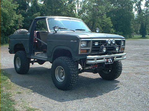 1986 Ford Bronco - This modified SUV features a roll cage and auxiliary lights, with a license plate reading '44'.