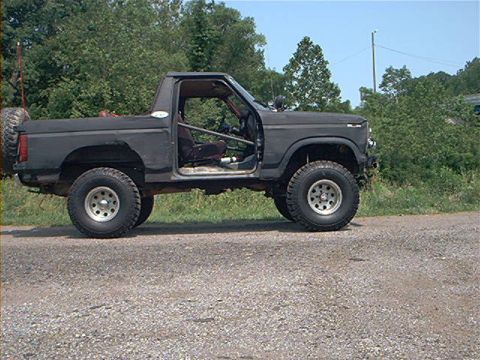 1986 Ford Bronco - This modified SUV, likely from the 1980s, has a roll cage and spare tire, suggesting off-road use.