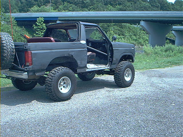 Dark gray 1986 Ford Bronco with doors removed and spare tire mounted on rear