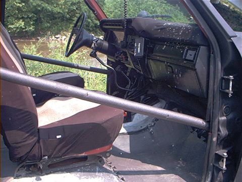 1986 Ford Bronco - The interior of a vehicle features a roll cage and aftermarket seat covers.
